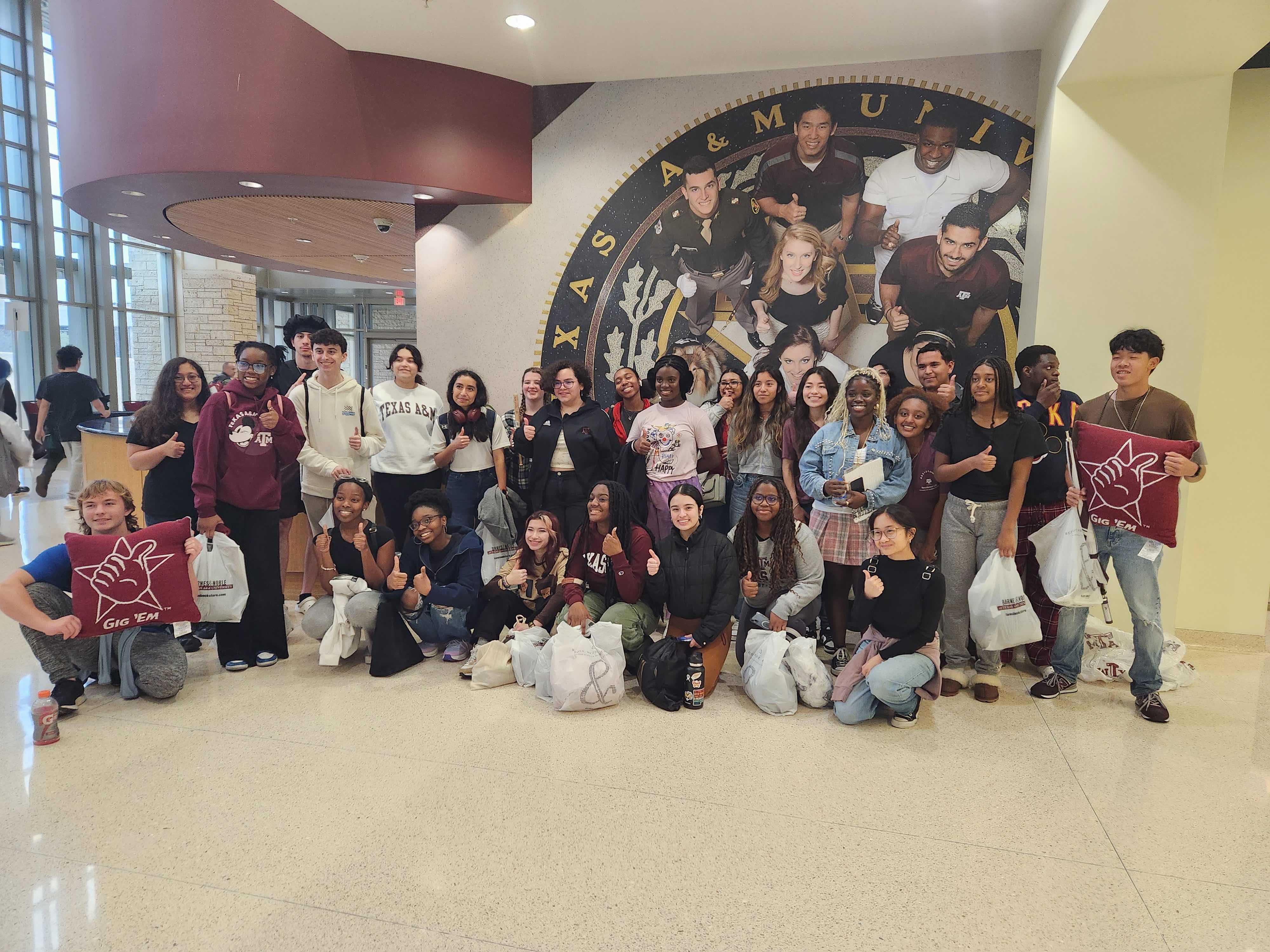 Students posing in front of a sign from Texas A&M